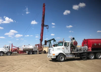 Close-up of a hot oiler truck operating in an oilfield, hoses connected and steaming