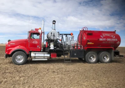 Side view of an oilfield hot oiler truck with visible hose connections